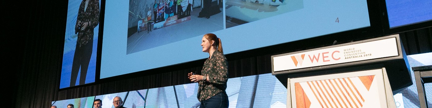 A woman in a dark-patterned top presents at a conference