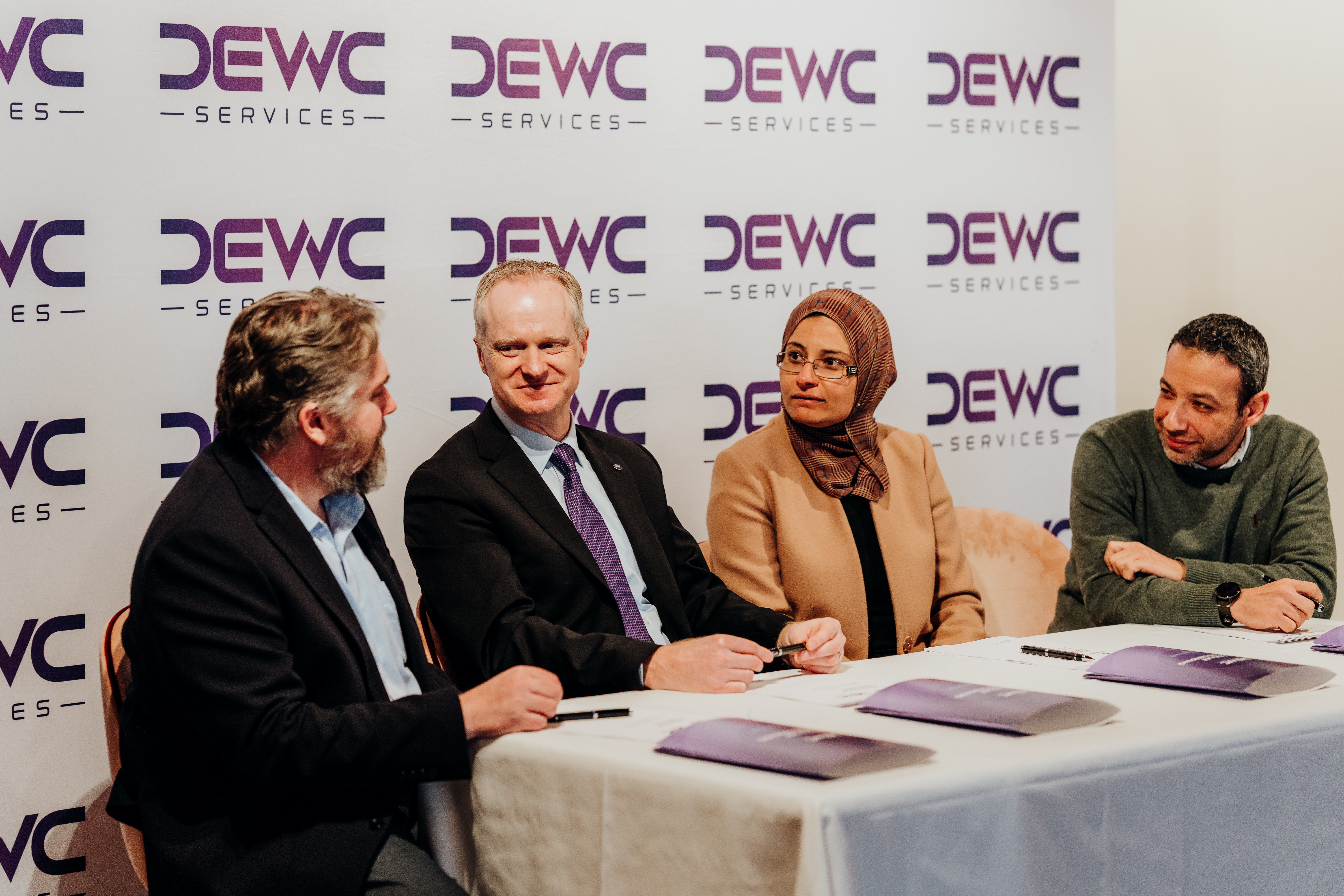 A group of four people sit at a panellists' table, in discussion